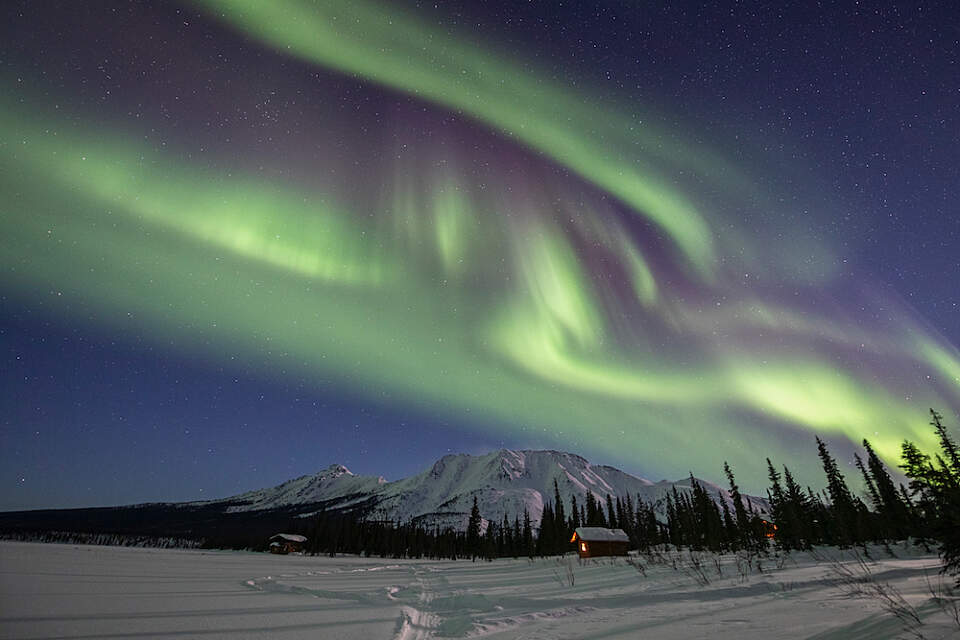Iniakuk Lake Wilderness Lodge in winter with the northern lights overhead
